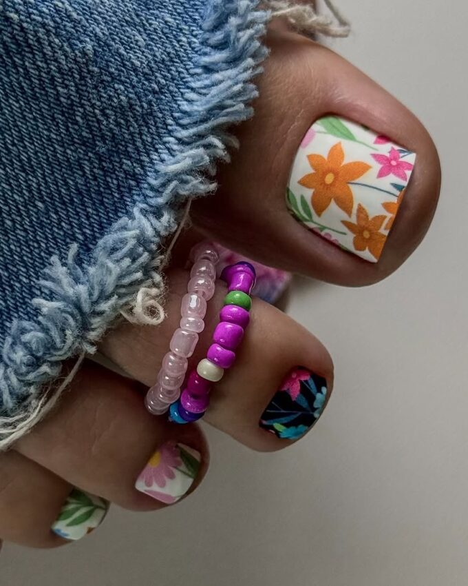 Pédicure blanche avec des motifs floraux colorés et un accent estival