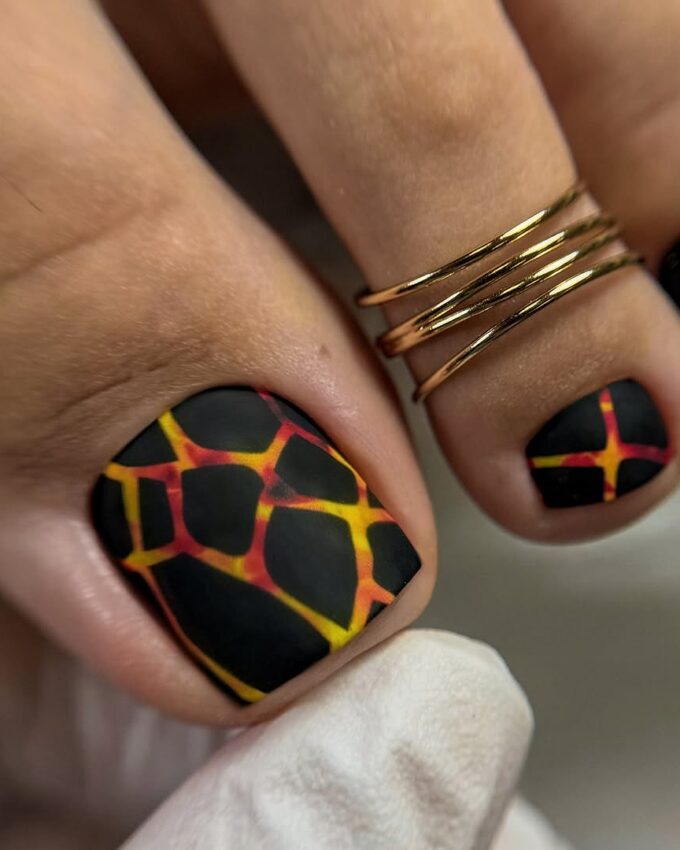 Pédicure noire avec motif girafe en jaune et rouge