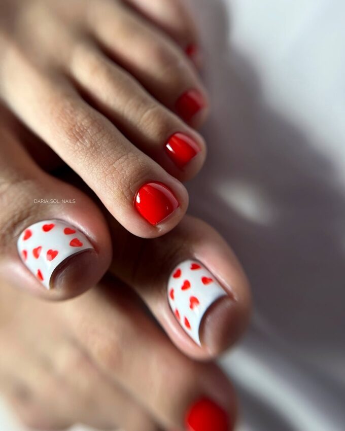 Pédicure avec vernis rouge et ongles blancs décorés de petits cœurs